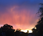 Photo of a sky with a sunburst of color from golden at the horizon to pink to deep purple overhead.